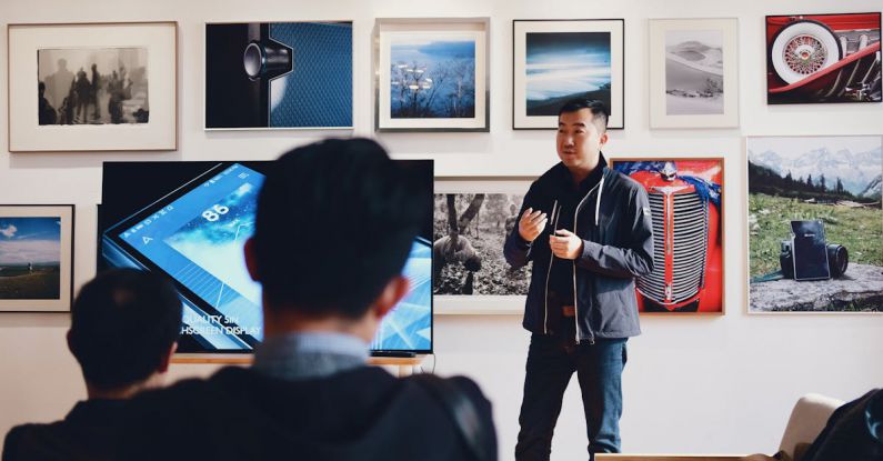 Exhibit - Man Beside Flat Screen Television With Photos Background