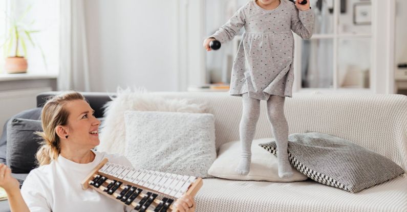 Plays - Little Girl Jumping on Couch while Mother Plays on Xylophone